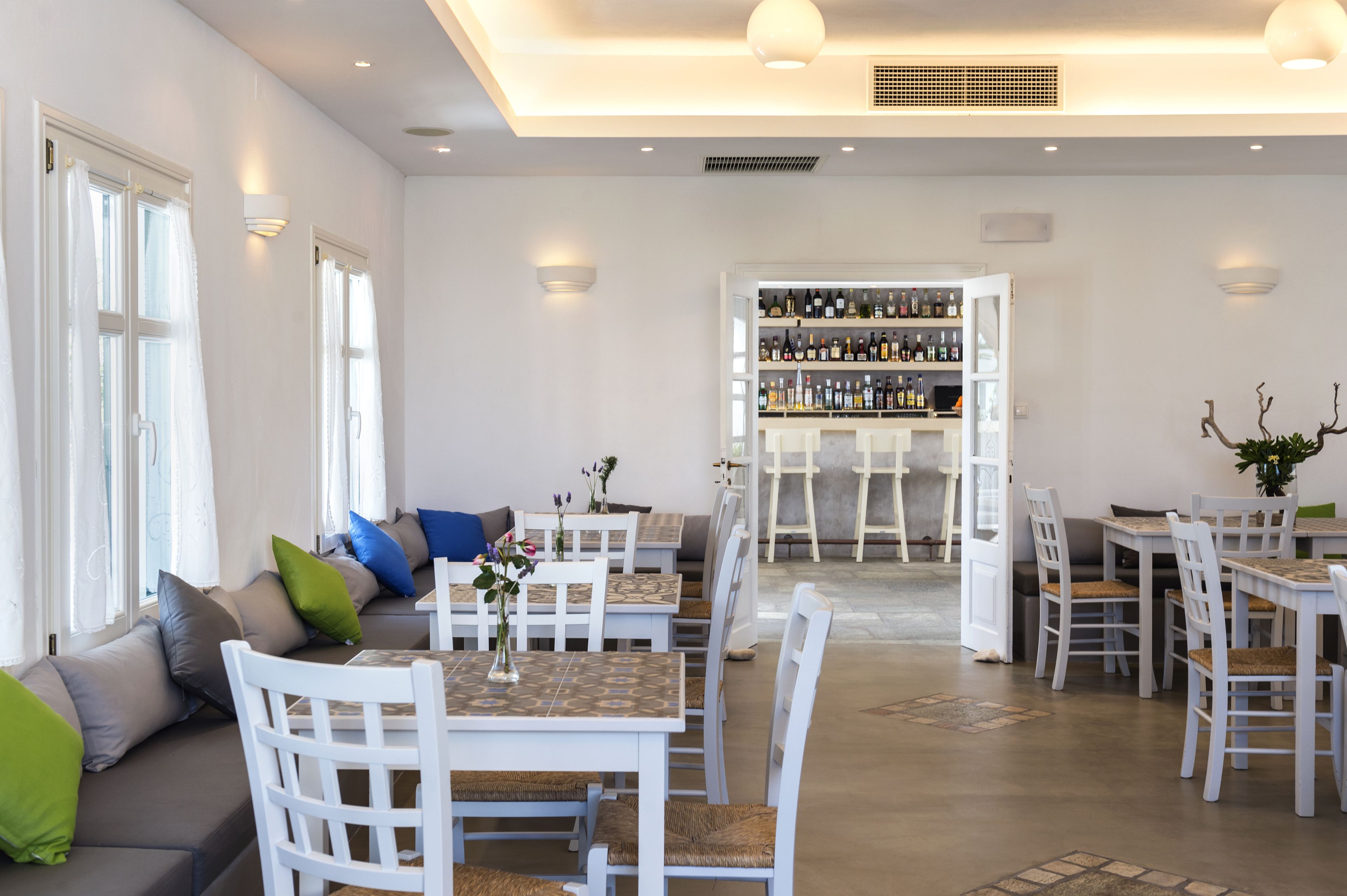 A restaurant with white furniture, a bar area, and a seating arrangement.