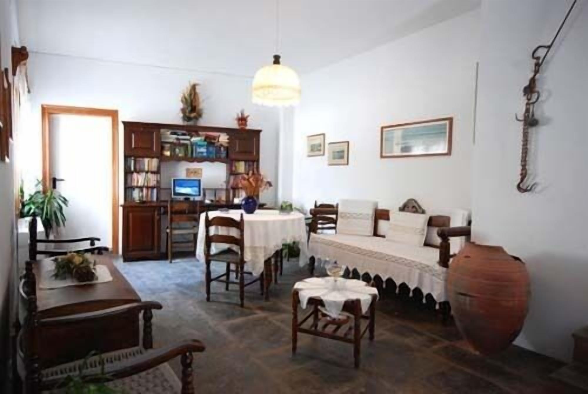 Una sala de estar acogedora con un sofá, una mesita de centro y una mesa de comedor. Se observa una estantería llena de libros y un televisor sobre un mueble.