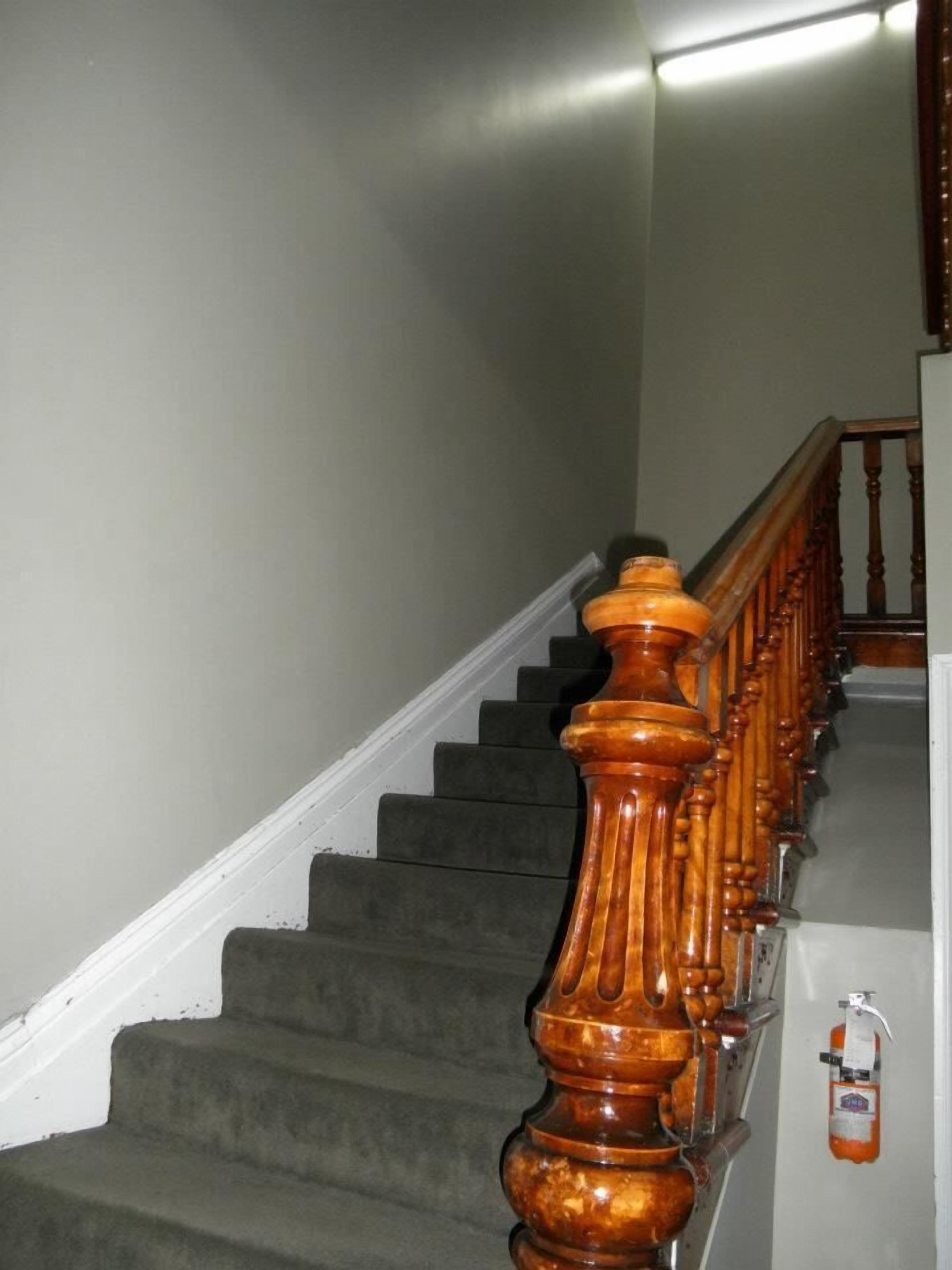 A staircase with wooden balusters and a fire extinguisher mounted on the wall.