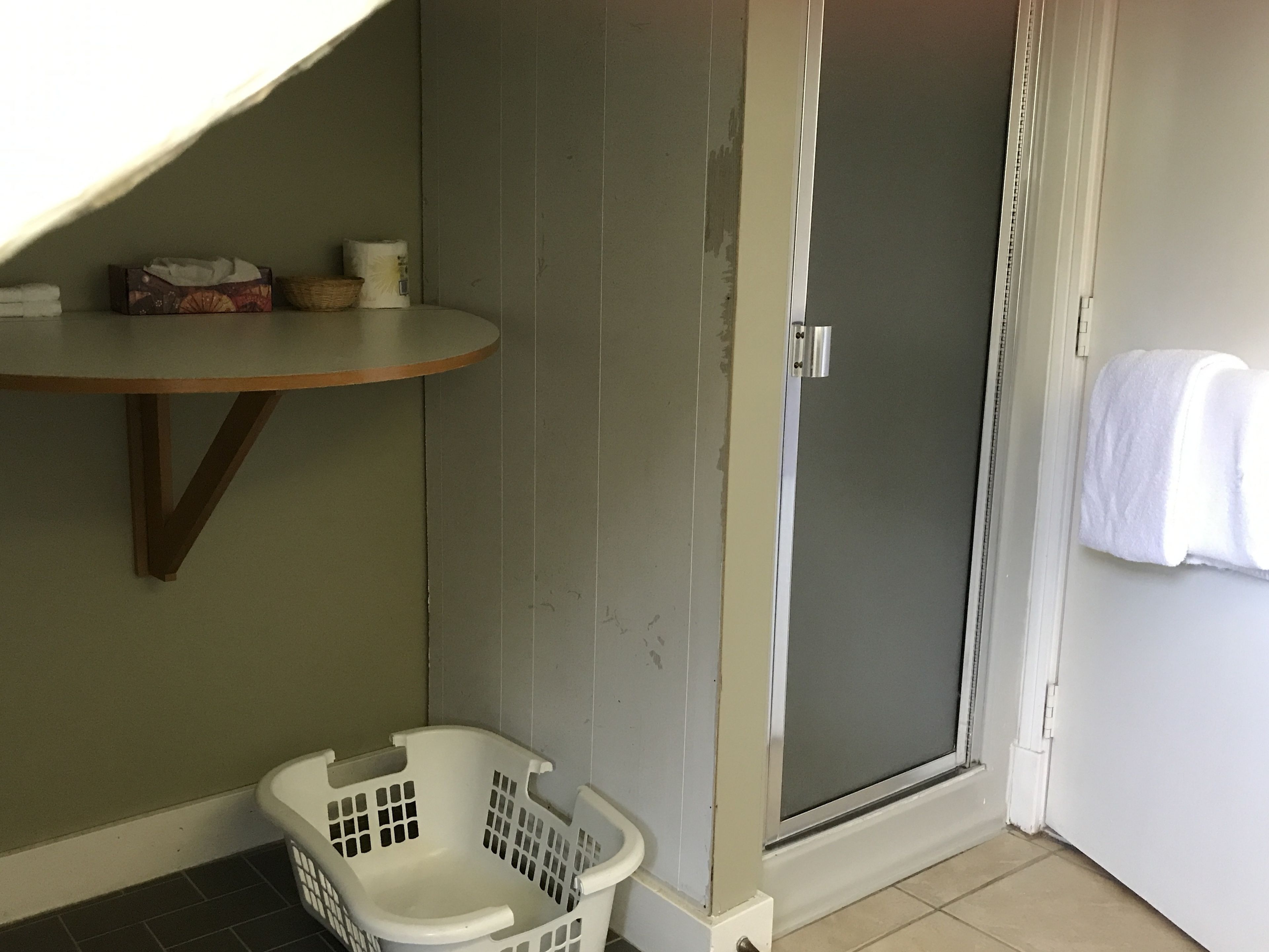 A laundry room with a washing machine, a drying rack, and a towel hanging on the wall.