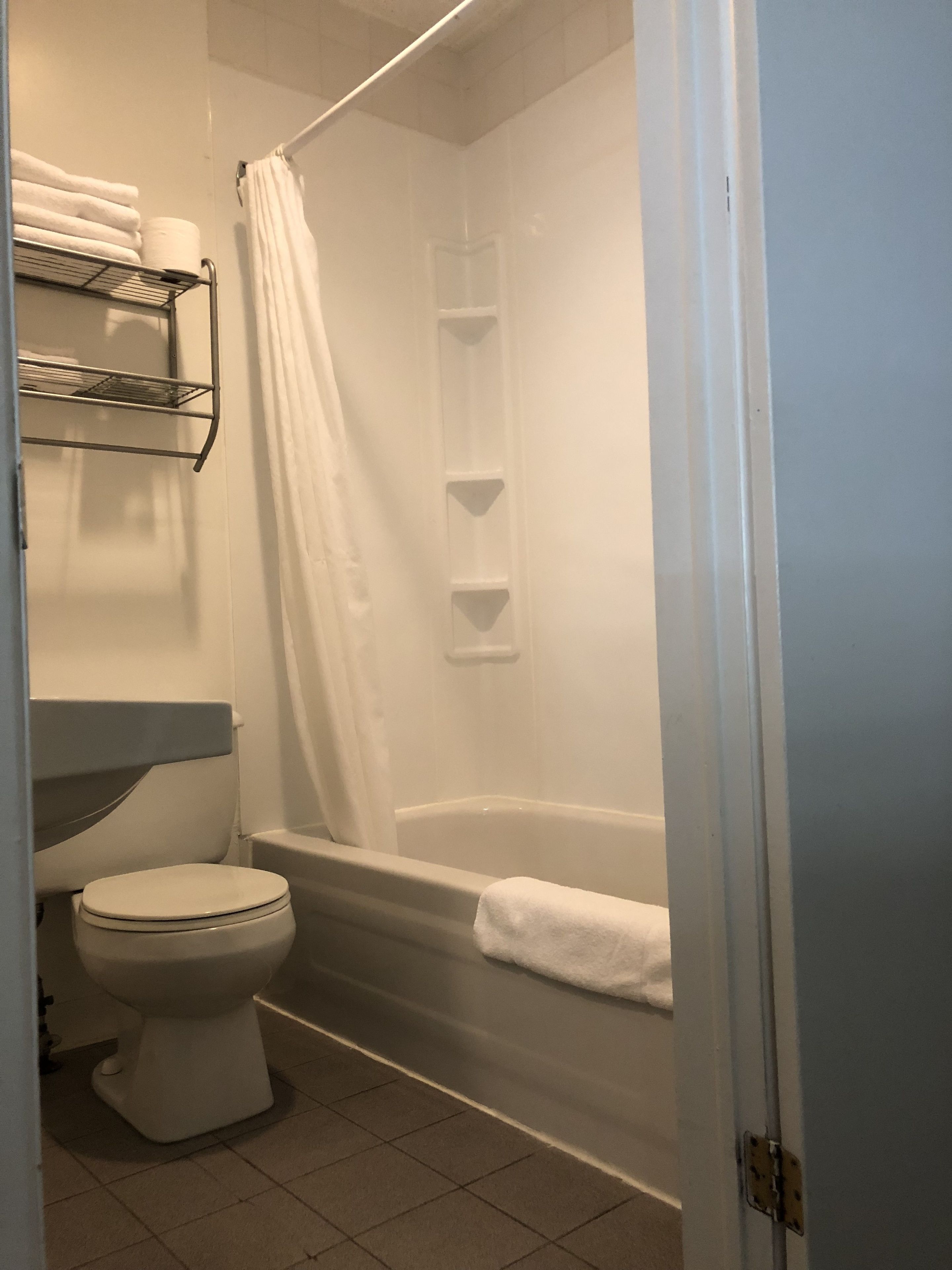 Et badeværelse med toilet, bruseforhæng og badekar.