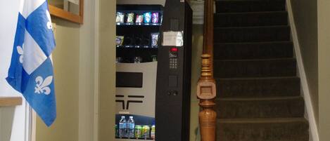 A staircase with a wooden handrail, a ceiling fan, and a vending machine in the background.