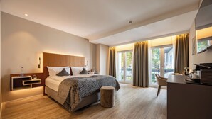 A modern hotel room with a large bed, a desk, and a view of the outdoors. - MAXIMILIAN MUNICH Apartments & Hotel  (Munich)