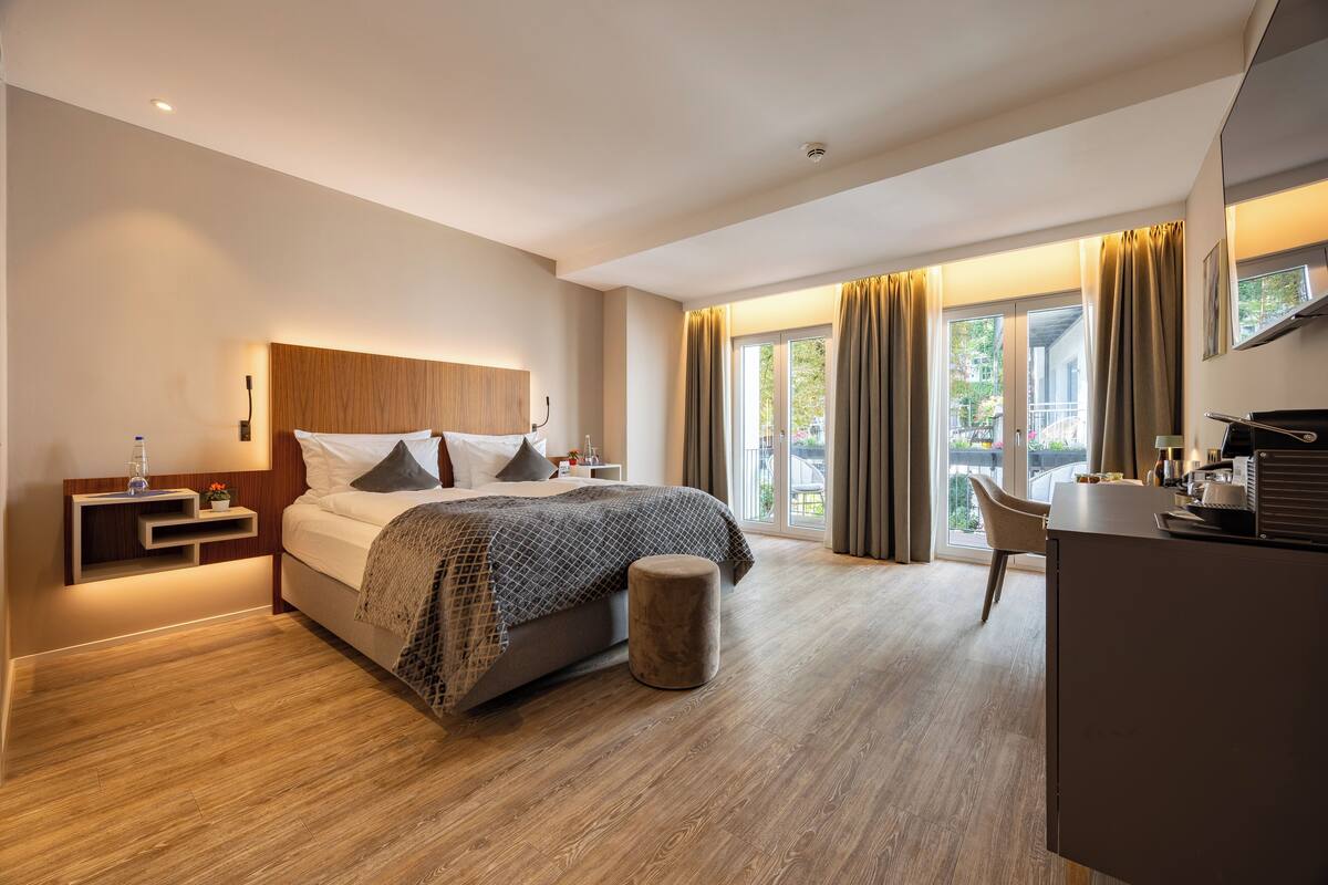 Habitació d'hotel moderna amb un llit gran, un escriptori i vista a l'exterior.
