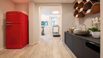 Una cocina moderna con un refrigerador rojo, estantes de madera y una cinta de correr al fondo.