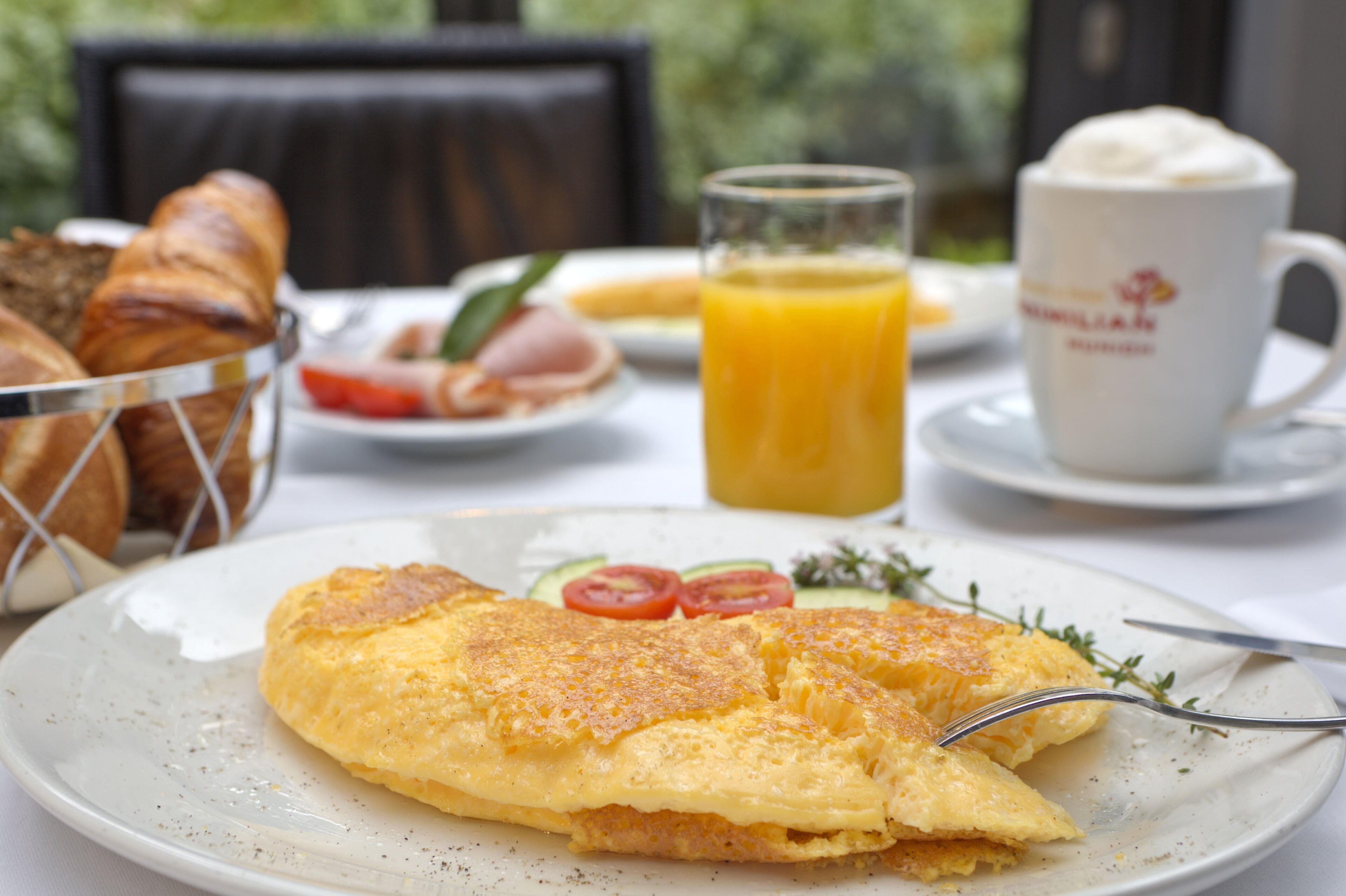 A breakfast setting with an omelette, toast, a glass of orange juice, and a coffee cup.