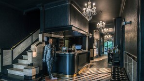 Un vestíbulo con piso a cuadros, una escalera, una zona de bar y un candelabro.