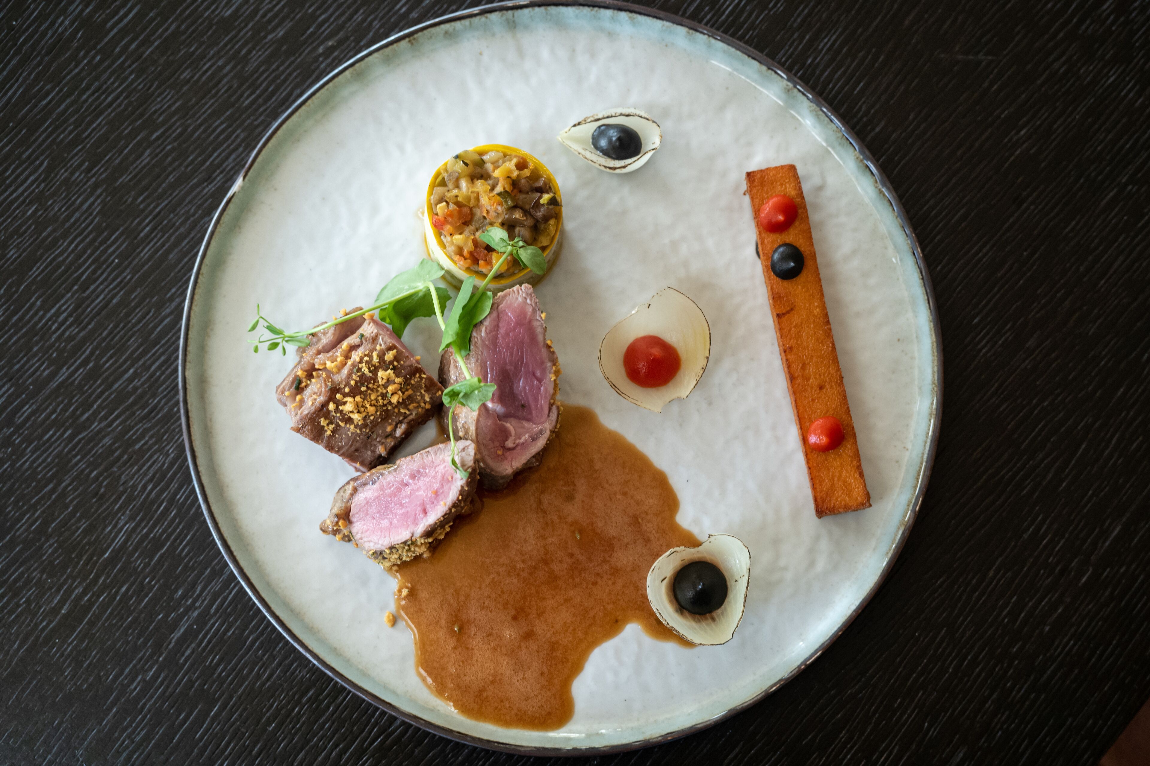 A plate with various food items, including meat, vegetables, and sauces.