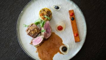 A plate with various food items, including meat, vegetables, and sauces.