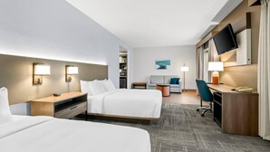 A hotel room with two beds, a desk, a chair, a TV, and a small seating area with a table and chairs. - Comfort Suites Gothenburg South (Gothenburg)
