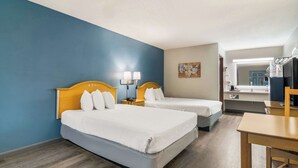 Une chambre d’hôtel avec deux lits, un bureau, une chaise et une salle de bain visible à travers une porte ouverte.
