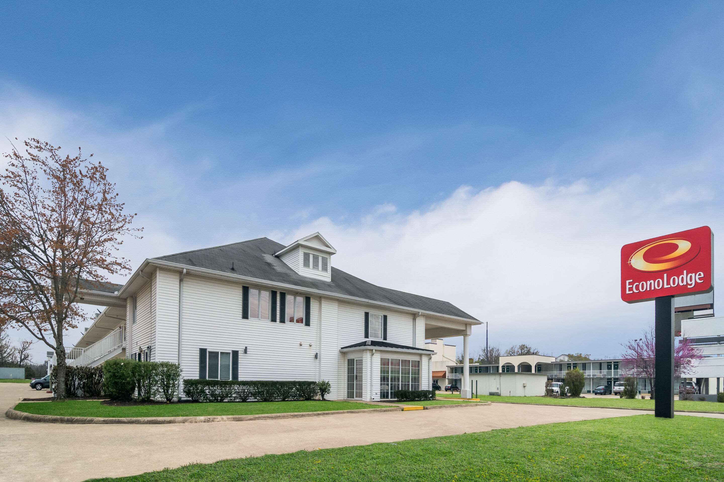 A two-story white building with a covered front porch and a sign for EconoLodge.