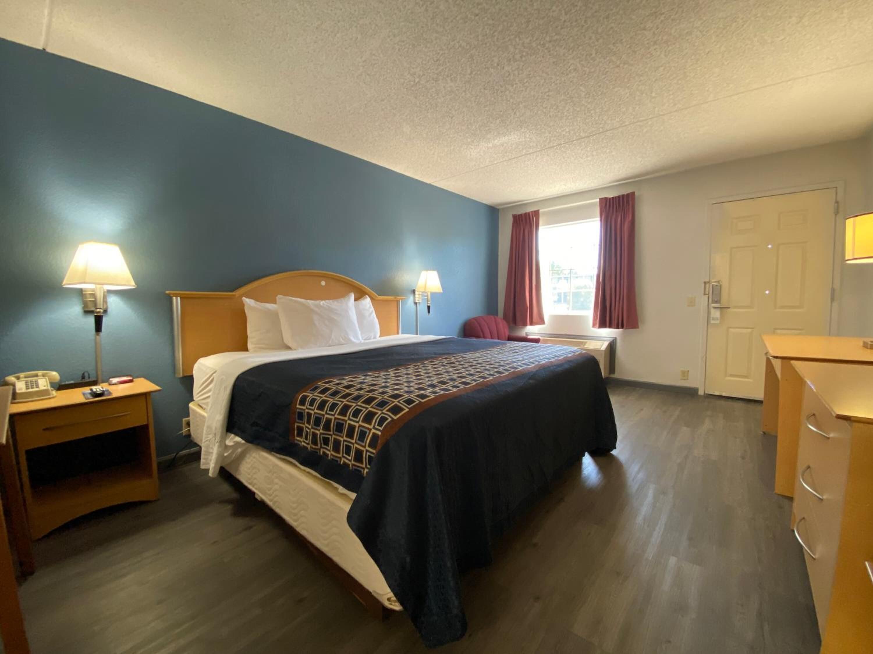 Una habitación de hotel con cama, mesitas de noche, escritorio y una silla.