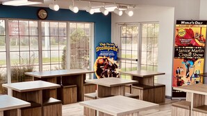 L’intérieur d’un restaurant est aménagé avec des tables et des bancs en bois, de grandes fenêtres et des affiches faisant la publicité d’un spectacle-dîner et d’un spectacle de cirque.