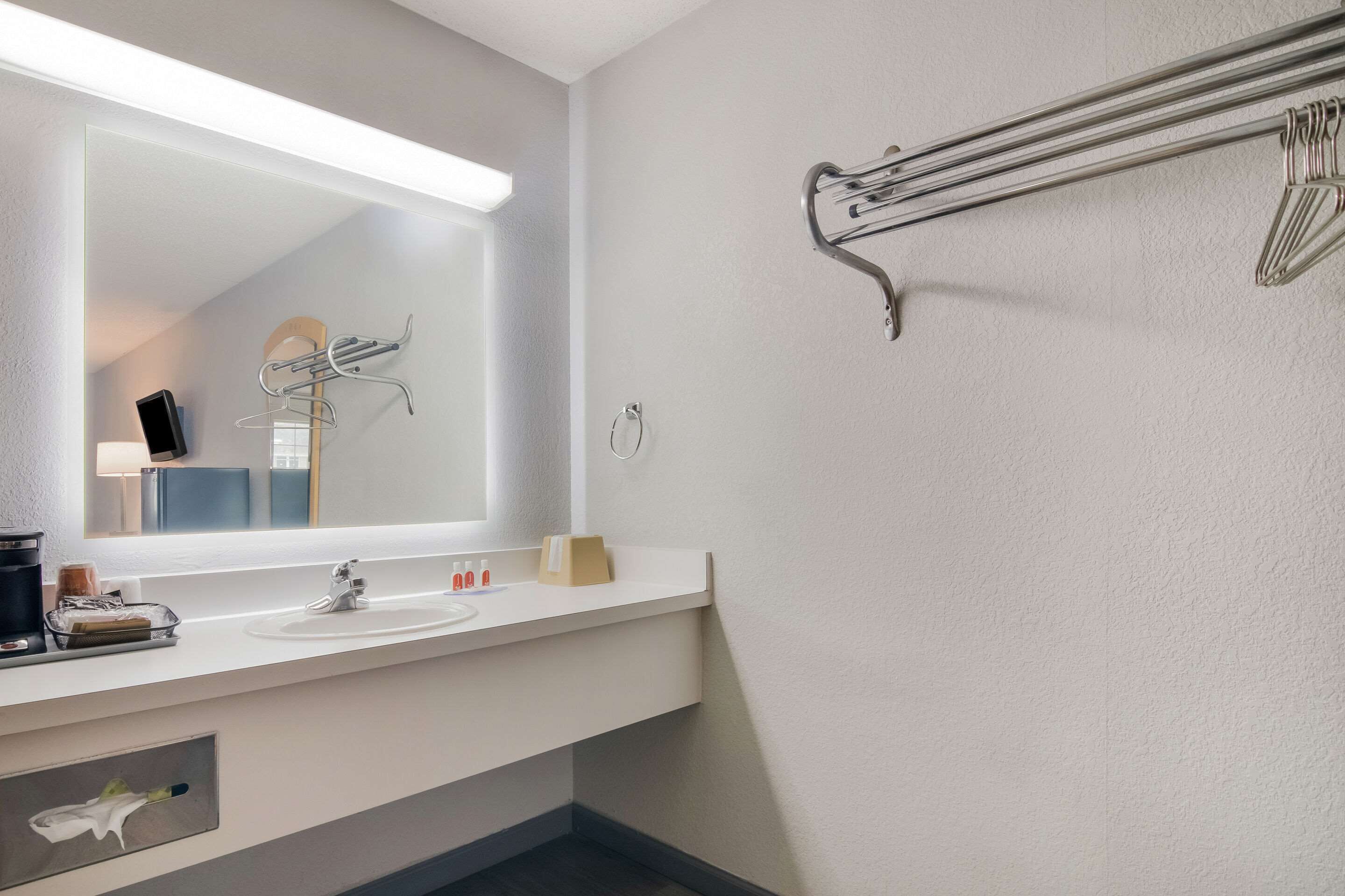 A modern bathroom with a large mirror, a sink, and a towel rack.