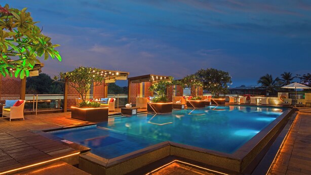 A pool area with lounge chairs and a pergola. - Holiday Inn Cochin by IHG (Kanayannur)