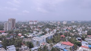 A cityscape with high-rise buildings, residential houses, and dense greenery.