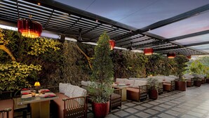 A restaurant with outdoor seating, covered by a roof, and surrounded by greenery. - Holiday Inn Cochin by IHG (Kanayannur)