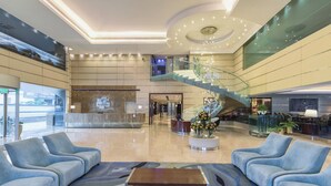 A spacious lobby with a central seating area, a staircase, and a reception desk. - Holiday Inn Cochin by IHG (Kanayannur)