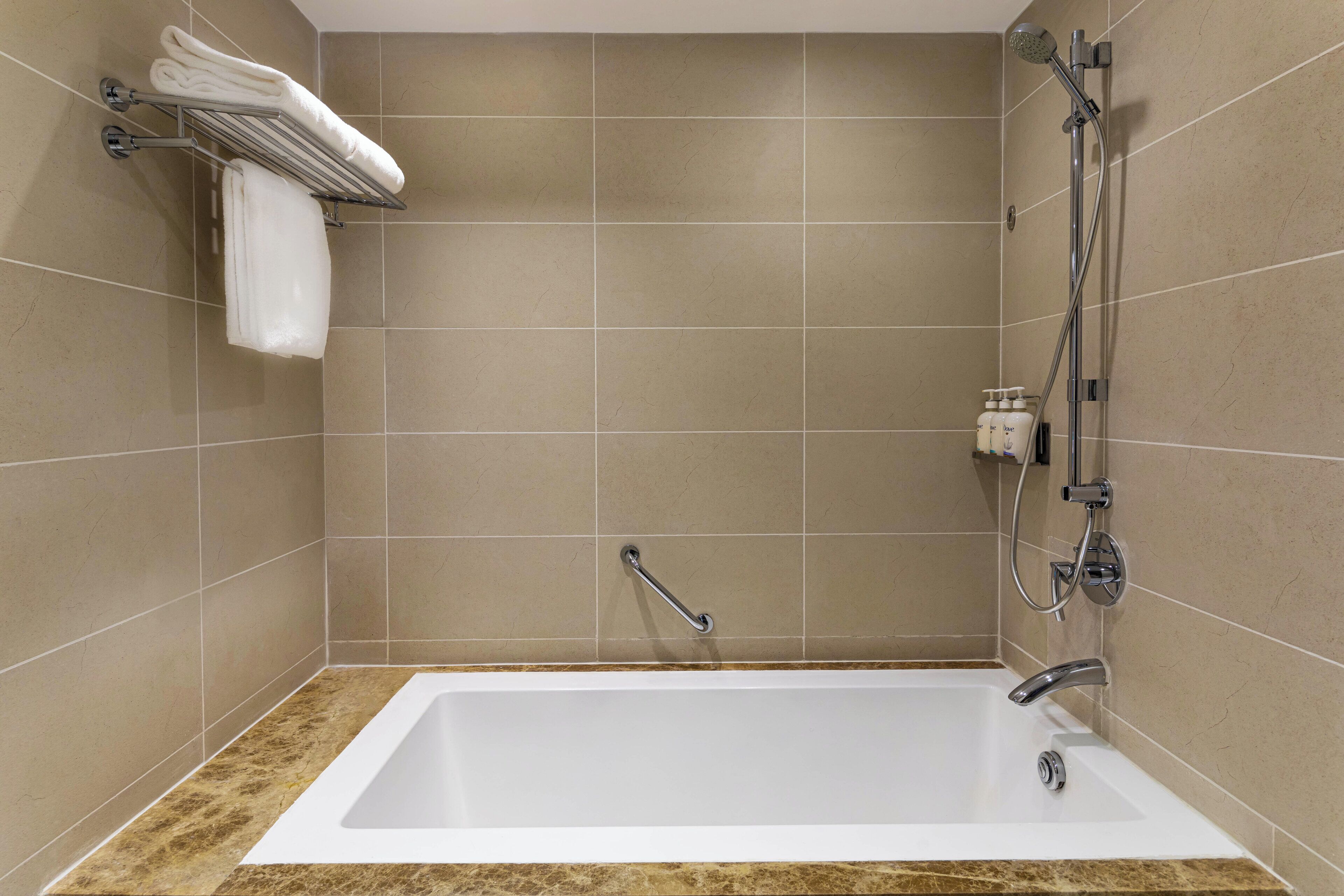 A modern bathroom with a bathtub, a shower, and a towel rack with folded towels.