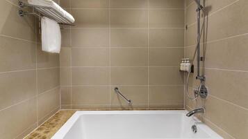 A modern bathroom with a bathtub, a shower, and a towel rack with folded towels.