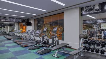 Un gimnasio con cintas de correr, elípticas y un estante de mancuernas.