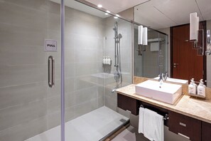 A modern bathroom with a glass-enclosed shower, a sink with a vanity, and a mirror.