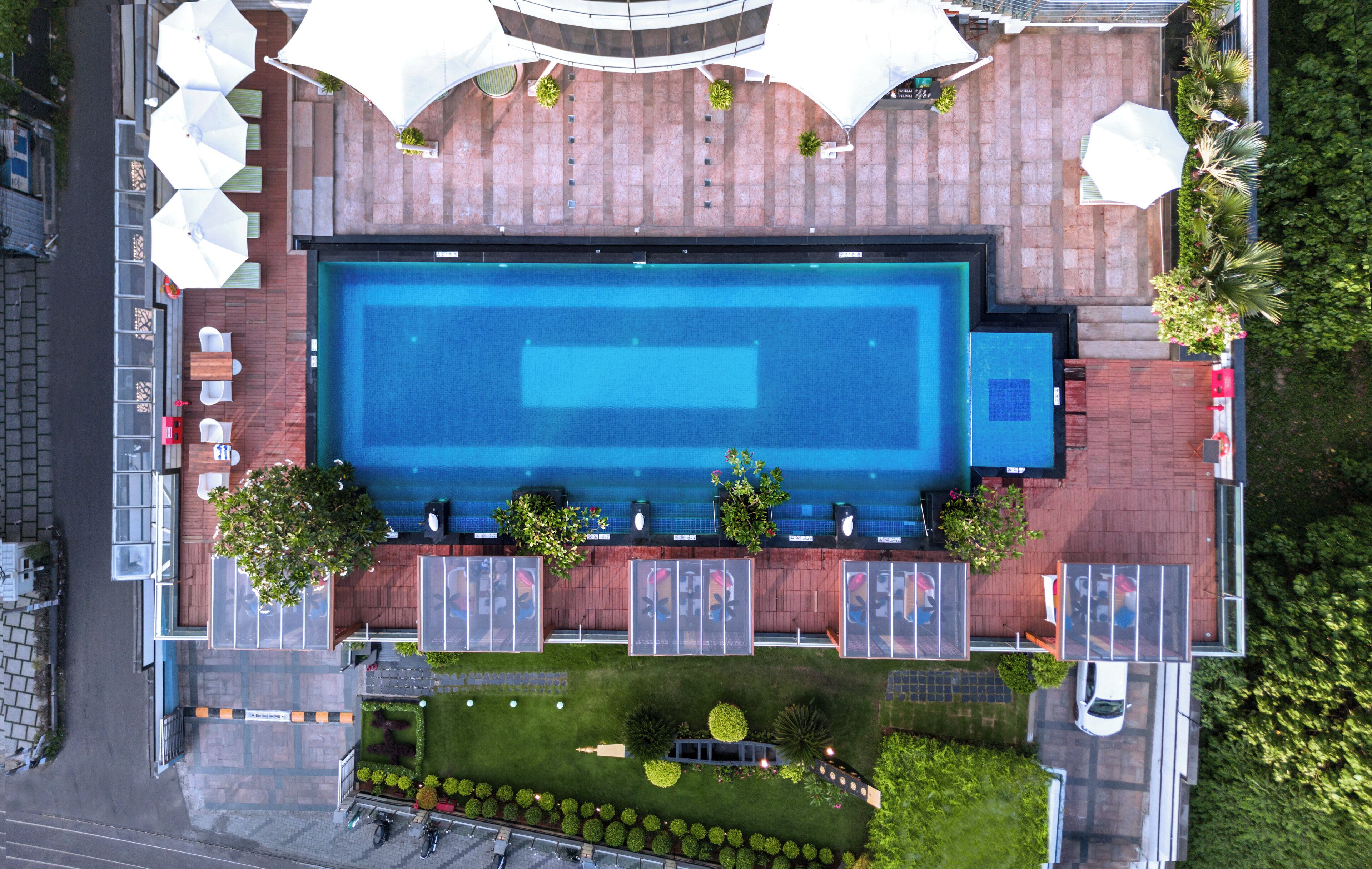 Vista aérea de un hotel con una piscina rectangular grande, zona de estar al aire libre y aparcamiento.