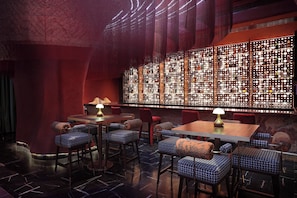 A dimly lit bar area with wooden tables and patterned bar stools. - Holiday Inn Cochin by IHG (Kanayannur)