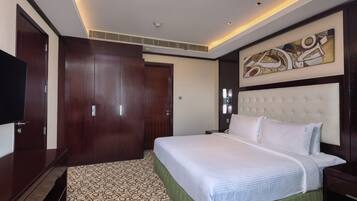Ein Hotelzimmer mit einem großen Bett, einem Kleiderschrank, einem Fernseher und einem an der Wand befestigten Kunstwerk.