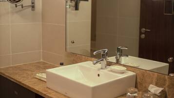 A modern bathroom with a large sink, two faucets, a mirror, and a towel rack.
