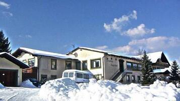 A building with a snow-covered roof and a van parked in front.
