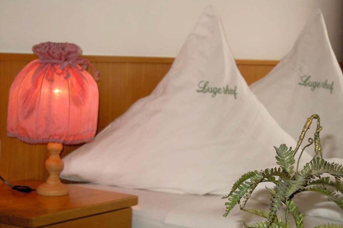 A bed with two pillows labeled "Lugehof" and a bedside lamp.