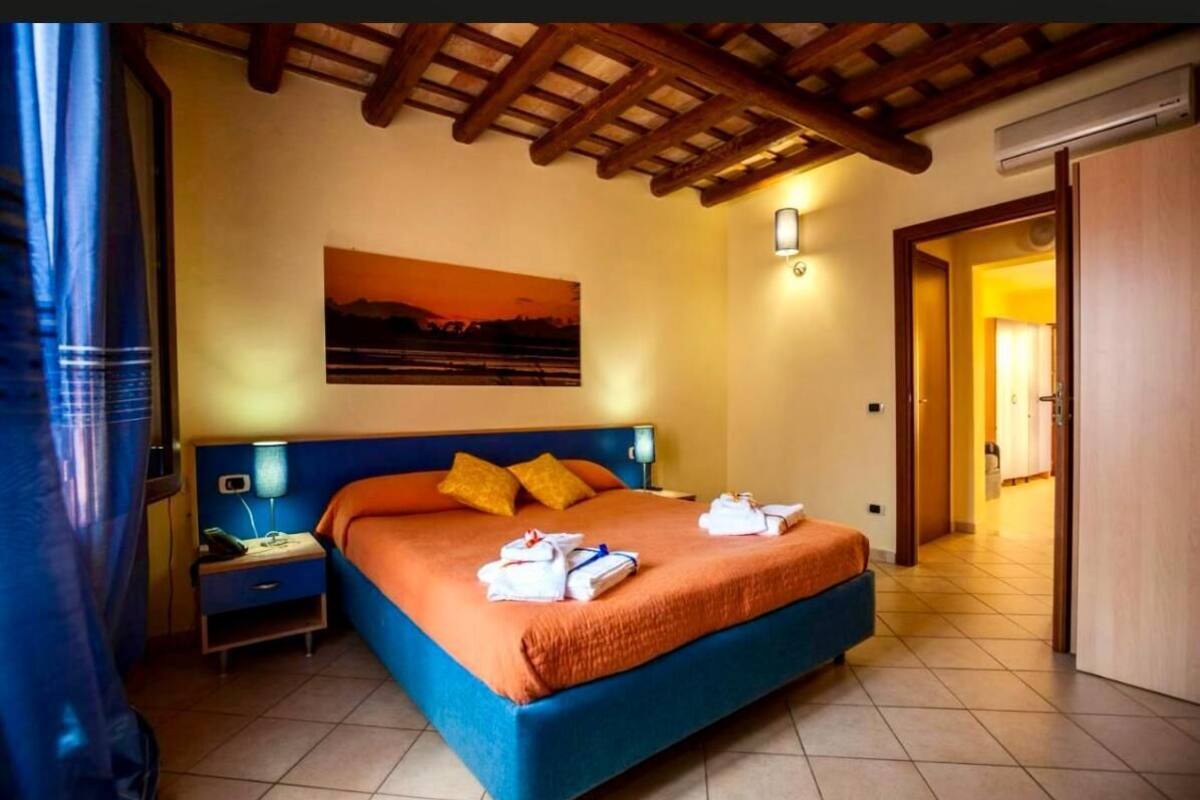 A bedroom with a bed, nightstands, a painting, and a door.