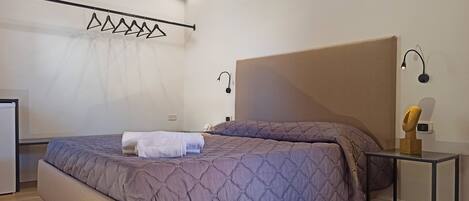 Une chambre à coucher avec un grand lit, une table de chevet et un luminaire suspendu.