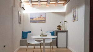 A modern dining area with a round table, two chairs, and a small refrigerator. - Residence Cortile Mercè (Trapani)
