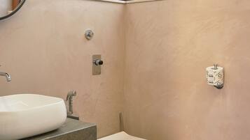 A bathroom with a white sink, a toilet, and a window above the toilet.