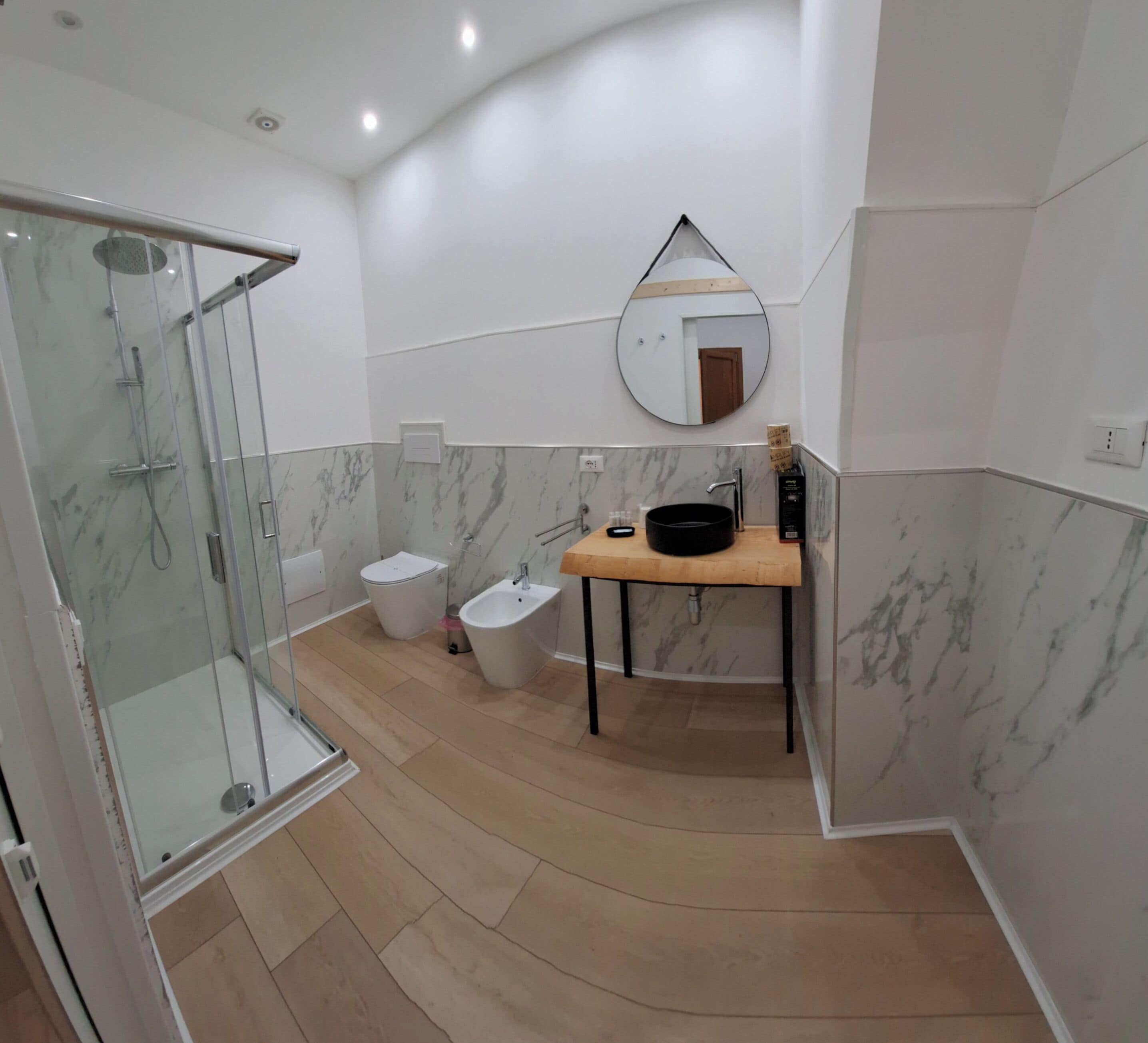A modern bathroom with a glass shower enclosure, a sink with a mirror, and a bidet.
