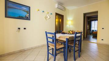 A dining area with a table set for four, chairs, a lamp, and a framed picture on the wall.