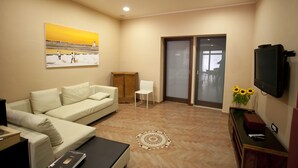 A modern living room with a sofa, a coffee table, a TV, and a painting on the wall. - Residence Cortile Mercè (Trapani)