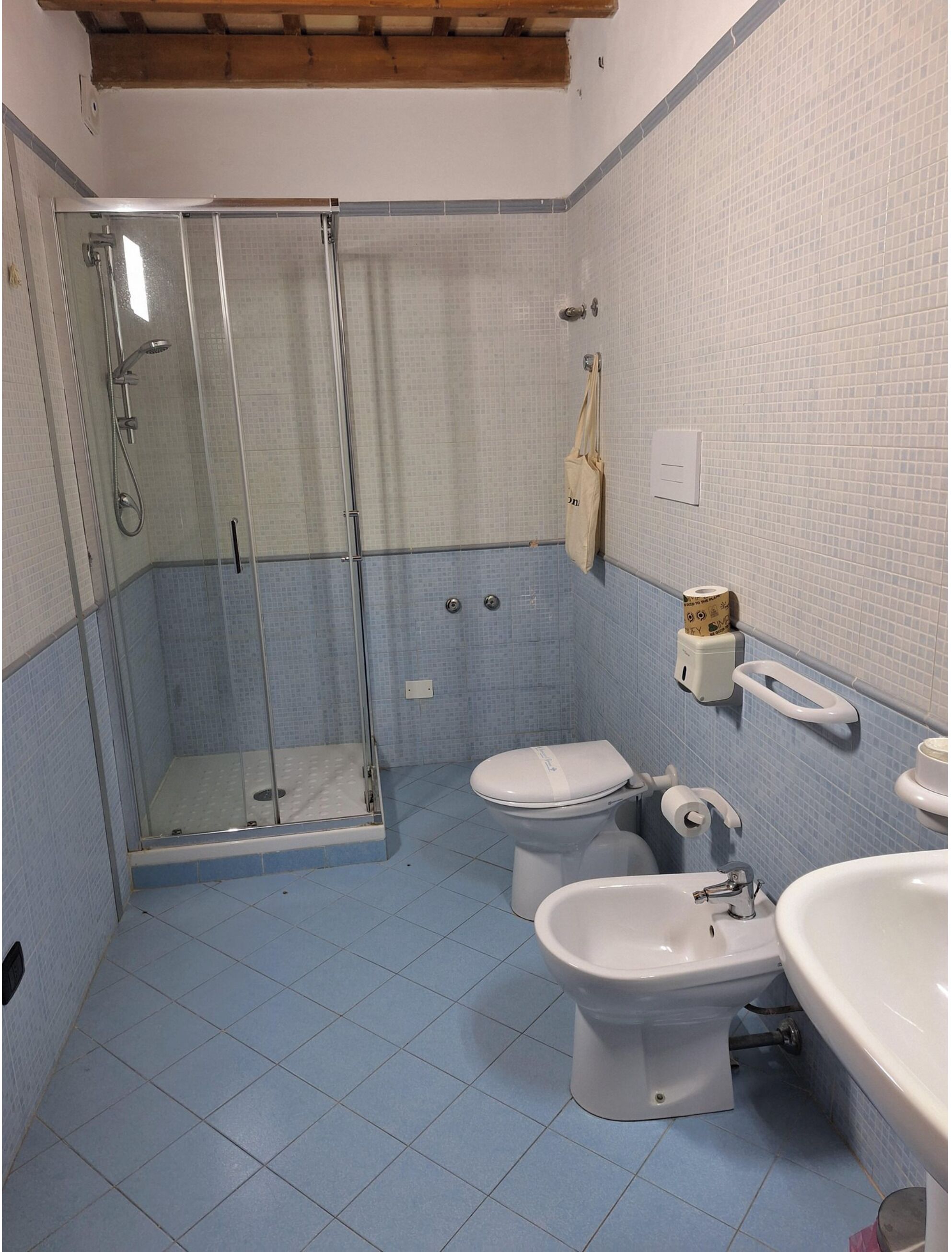 A bathroom with a glass-enclosed shower, two toilets, a bidet, and a sink.