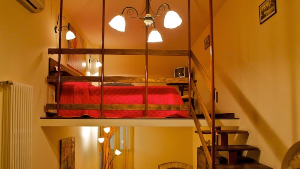 A cozy loft bedroom with a bunk bed, a wooden staircase, a dining table, and a sofa. - Albergo Tripoli - Guest House (Corato)