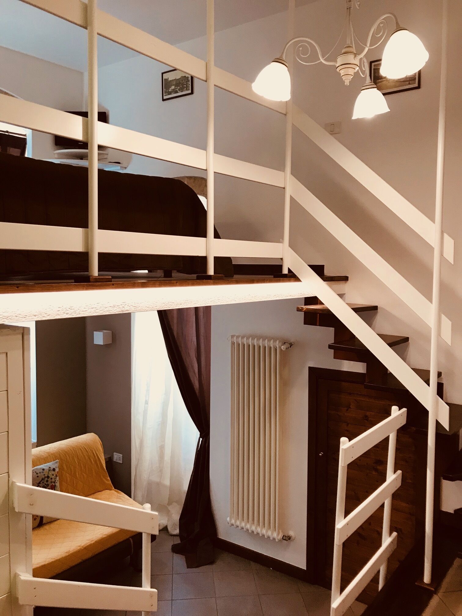 Un interior moderno con un dormitorio tipo loft, una escalera y un radiador.