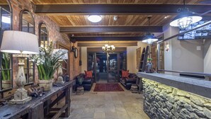 A lobby with a stone wall, wooden ceiling, and a reception desk. - Excellent Guest House (Cape Town)