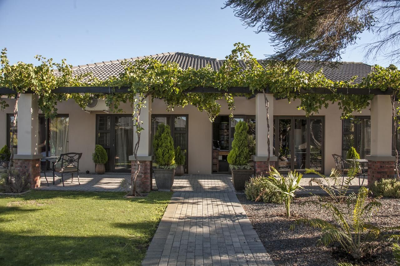 A house with a covered patio, potted plants, and a brick pathway.