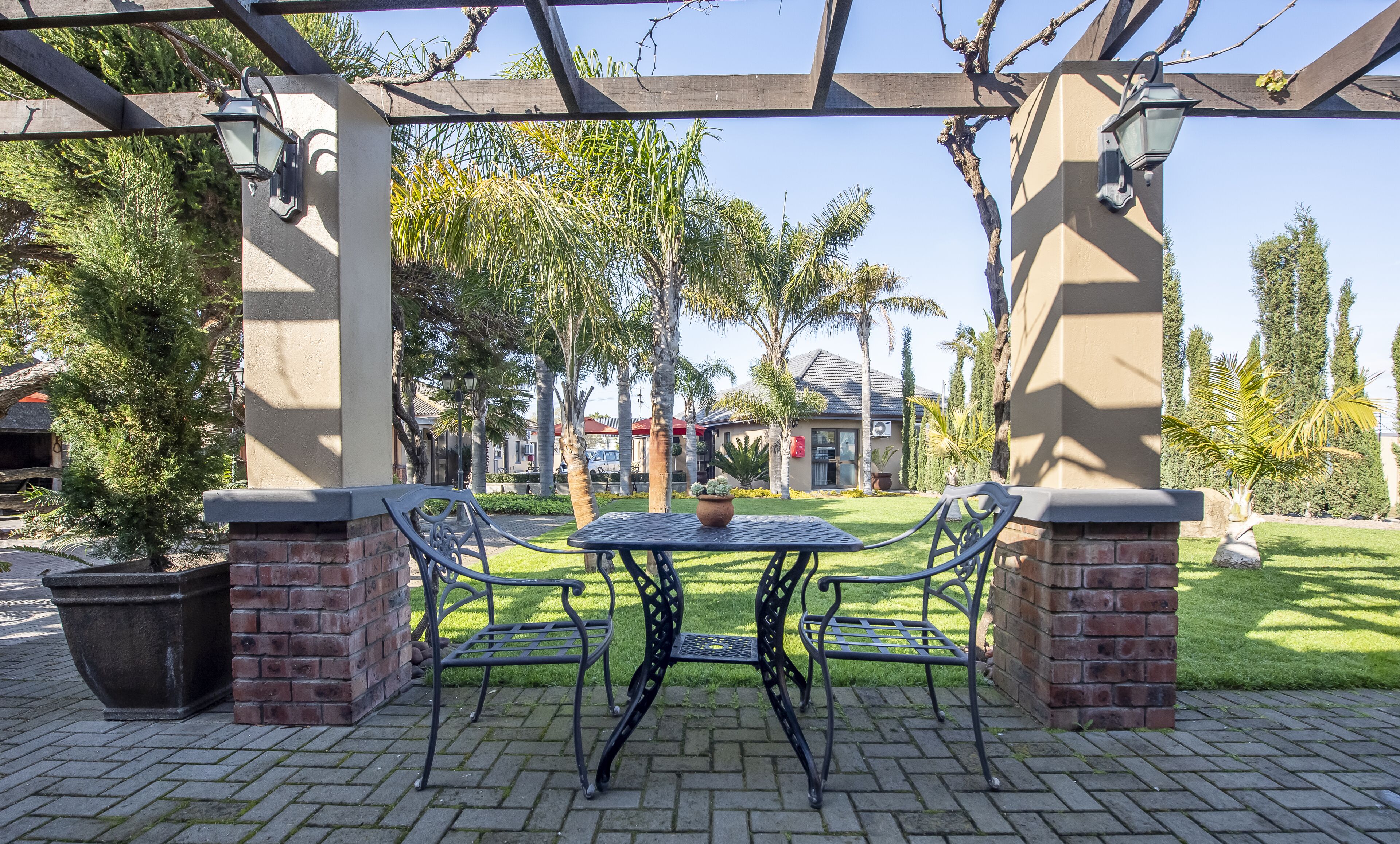 Eine Terrasse im Freien mit Tisch und Stühlen, umgeben von Ziegelstützen und einer Pergola.