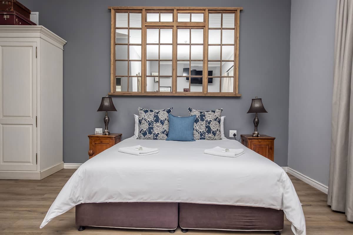 Quarto com uma cama grande, duas mesas de cabeceira, um espelho e um guarda-roupa.