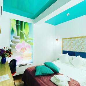A hotel room with a bed, pillows, a vase with flowers, and a wall with a nature-themed mural. - Hotel Marea Neagra (Constanta)