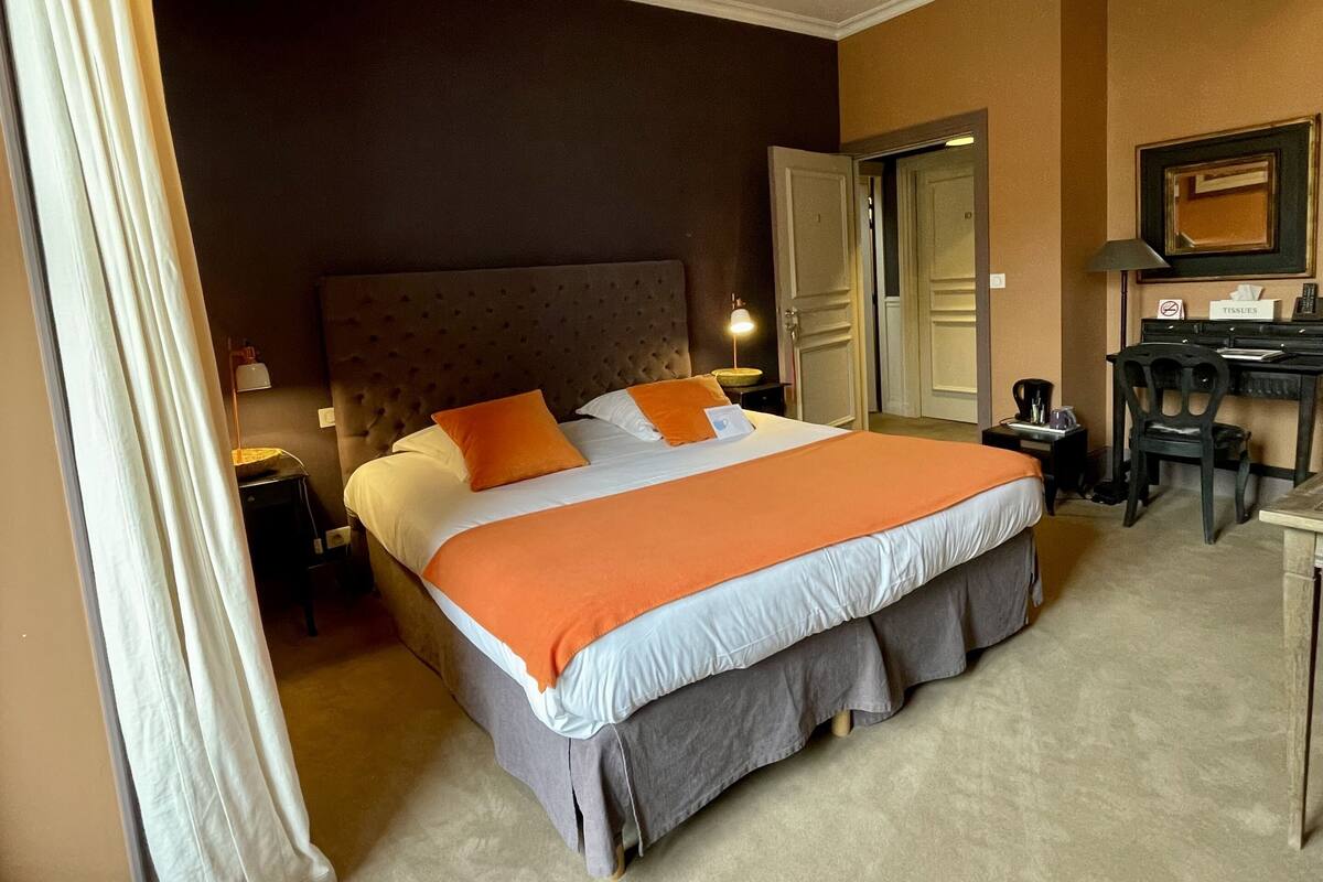 Una habitación de hotel con una cama grande, un escritorio y una silla.