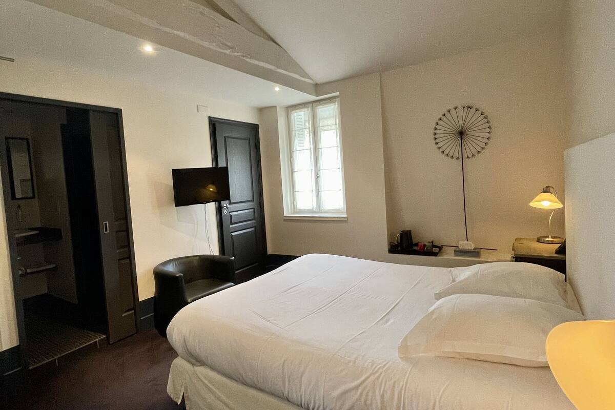 Un dormitorio con una cama grande, un armario, un escritorio, una silla y una lámpara de pie.
